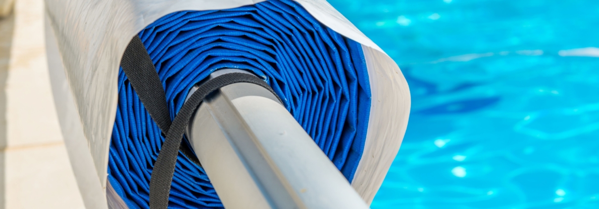 Poolabdeckung aufgerollt am Beckenrand neben klarem Wasser