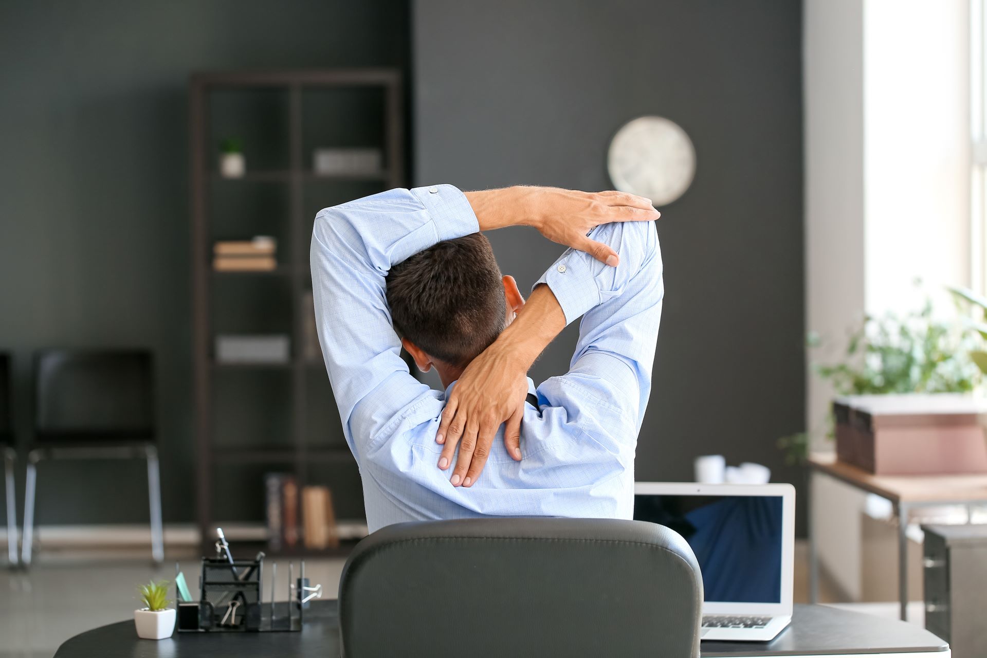 Mann dehnt sich am Arbeitsplatz mit Schreibtischgestell höhenverstellbar